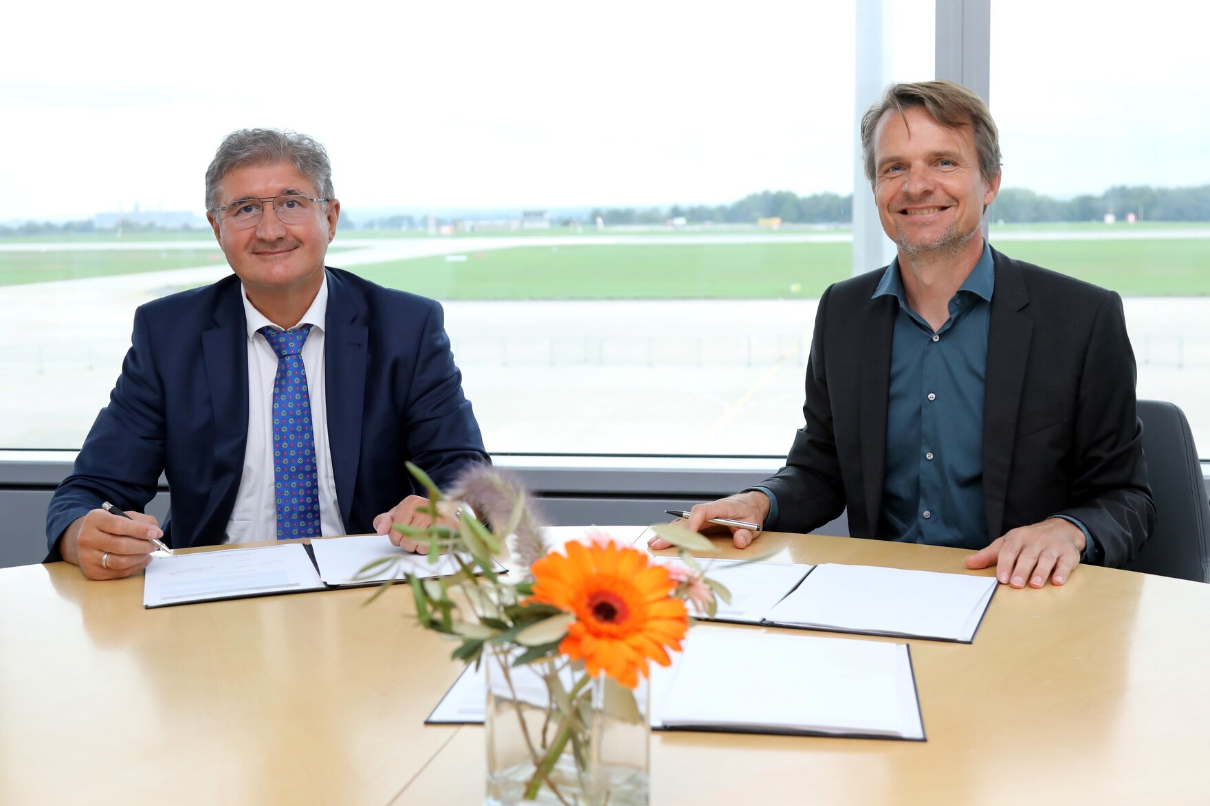  Staatssekretär Prof. Thomas Popp und der Vertreter des Entwicklungsdienstleisters Seitenbau GmbH zeigen die unterschriebenen Verträge in die Kamera. .