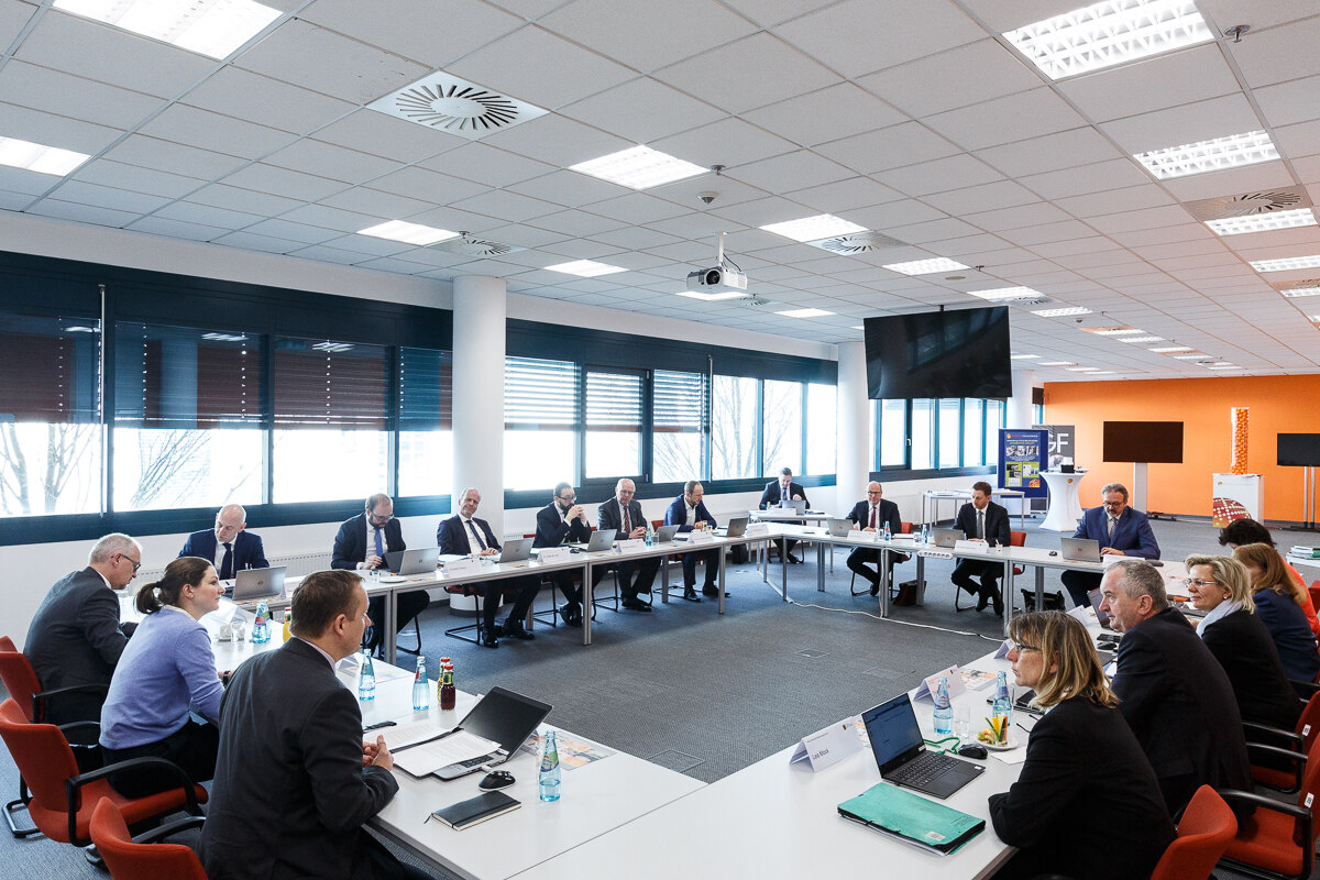 Männer und Frauen halten an einem Tisch ein Meeting ab.